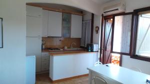 cocina con armarios blancos y nevera blanca en Residence Sottomonte, en Golfo Aranci