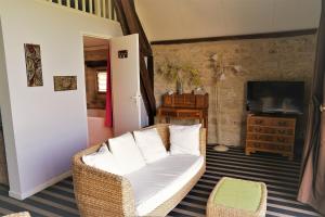 a living room with a white couch and a television at Hôtel Restaurant Le Mûrier de Viels - Grand Figeac in Causse et Diege