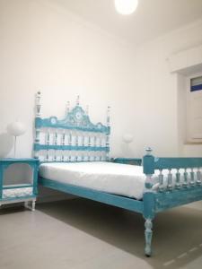 uma cama azul num quarto com uma parede branca em Casa da Madrinha I em Monte Gordo