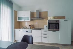 a kitchen with white cabinets and a microwave at Apartmani Josip in Podstrana