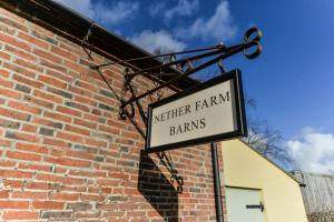 Znak mówiący, że ani rolnicy, ani stodoły przymocowane do budynku ceglanego w obiekcie Nether Farm Barns w mieście Ashbourne