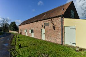 un ancien bâtiment en briques rouges avec deux portes de garage dans l'établissement Nether Farm Barns, à Ashbourne