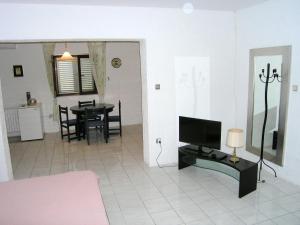 a living room with a television and a table with chairs at Apartman Kucer in Krk