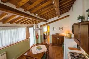 a kitchen with wooden ceilings and a table and a refrigerator at Agriturismo La Villa Romita in Tavarnelle in Val di Pesa