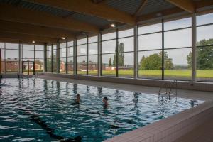 twee kinderen zwemmen in een zwembad met ramen bij Park Hotel Kelmis in Kelmis