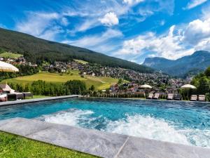 una piscina con vista su una città e sulle montagne di Alpin & Vital Hotel La Perla a Ortisei