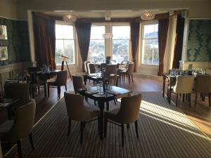 a dining room with tables and chairs and windows at Royal Victoria Hotel Snowdonia in Llanberis