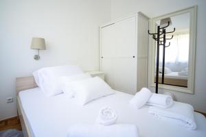 two white beds in a room with a mirror at Apartments Villa Perla in Rovanjska