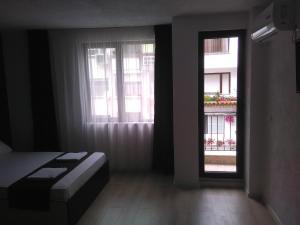 Zimmer mit 2 Fenstern und einem Bett in einem Zimmer in der Unterkunft Apartments Hristovi in Sandanski