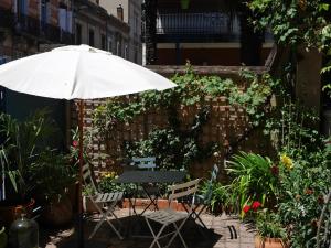an umbrella and a table and chairs in a garden at Les Loges des Chalets in Toulouse
