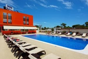 a swimming pool with lounge chairs next to a building at Zodiaco in Quarteira