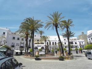 ein Parkplatz mit Palmen vor einem Gebäude in der Unterkunft Casa Romántica "La CHELA" in Vejer de la Frontera