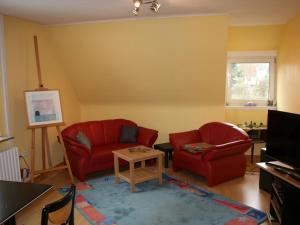 ein Wohnzimmer mit 2 roten Stühlen und einem TV in der Unterkunft Ferienwohnung Ruhepol in Vellmar