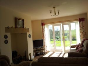 a living room with a couch and a sliding glass door at Hamsteels Hall Cottages in Langley Park
