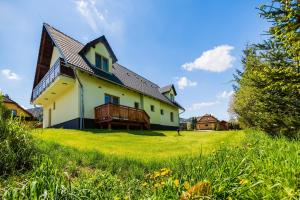 a house on a hill with grass and flowers at Penzion U Barana in Trojanovice