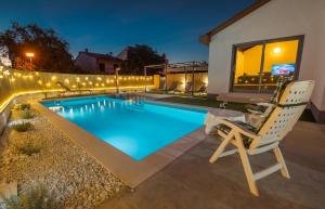 a swimming pool with a chair next to a house at Kuntrada 45 Holiday Home - Heated & Kids Pool in Fažana
