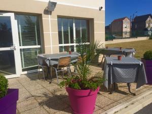 a patio with two tables and chairs and plants at Première Classe Epernay in Épernay