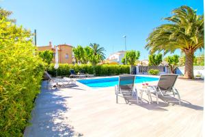 a villa with a swimming pool with chairs and a table at LEON INMO Villa Palmera - 10337 in Empuriabrava