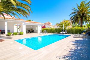 a swimming pool in the backyard of a house with palm trees at LEON INMO Villa Palmera - 10337 in Empuriabrava