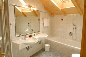 a bathroom with a sink and a tub and a mirror at Hotel Pra Tlusel in Selva di Val Gardena