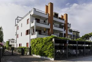 ein weißes Apartmenthaus mit grüner Hecke in der Unterkunft Residence Vecchio Faro in Cavallino-Treporti