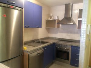 ビリャホヨサにあるApartamento En La Cala De Villajoyosaのキッチン(青いキャビネット、ステンレス製の冷蔵庫付)