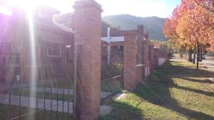 a fence with a brick pillar next to a building at Cabañas Simpson in Santa Rosa de Calamuchita