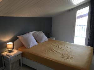 a bed with white pillows and a window in a room at Appart AQUITANIA, PLAGE in Capbreton