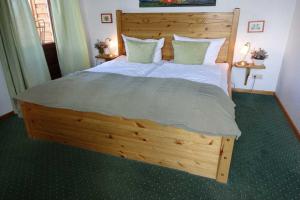 Un dormitorio con una gran cama de madera con sábanas y almohadas blancas. en Landhaus Ostseeblick en Kronsgaard