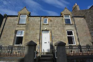 an old stone house with a white door at St Magnus Self Catering Lerwick in Lerwick