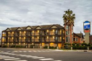 a hotel on the corner of a street with a palm tree at Executive Inn & Suites Sacramento in Sacramento