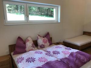 Schlafzimmer mit einem Bett mit lila und rosa Kissen in der Unterkunft Ferienhaus Grobauer II in Schwarzenberg am Bohmerwald