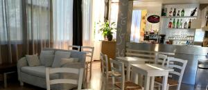 a bar with white chairs and a couch and a counter at Alice Hotel in Cervia
