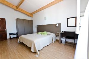 a bedroom with a bed and a desk and a table at Hôtel Les Lentisques in Cargèse