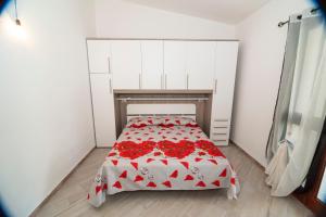 ブドーニにあるSant'Anna Apartmentsの赤い花のベッドが備わる小さなベッドルーム1室が備わります。