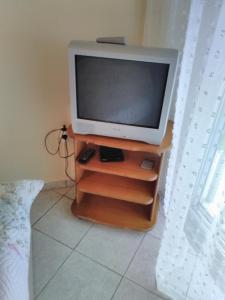 a television sitting on a wooden stand in a room at Zefi's Apartment in Nea Peramos