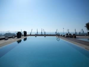 a swimming pool with windmills in the background at The Met Hotel Thessaloniki, a Member of Design Hotels in Thessaloniki