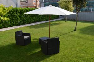 two chairs and an umbrella on a lawn at B&Be Home in Tollo