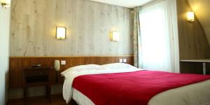 a bedroom with a large bed with a red blanket at Hôtel Restaurant Maison Blanche in Rungis