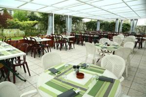 a patio with tables and white chairs and tables and tablesearcher at Hôtel Restaurant Maison Blanche in Rungis