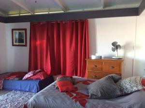 a bedroom with two beds and red curtains at Bungalow Premium Tahiti in Punaauia