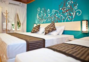 una camera da letto con due letti e una parete blu di Stingray Beach Inn a Maafushi