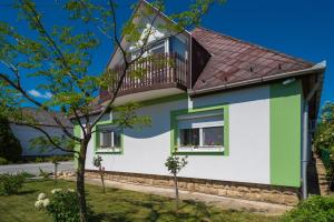 ein grünes und weißes Haus mit einem Balkon in der Unterkunft Andrea Apartmanház in Balatongyörök