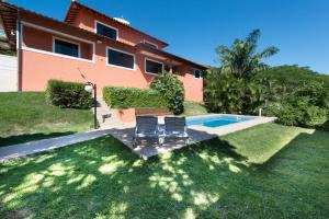 a house with a swimming pool and two chairs in the yard at Casa De Carlos in Búzios