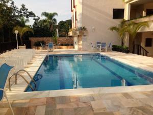 a swimming pool with chairs and a building at Apartamento Largo dos Coqueiros in Riviera de São Lourenço