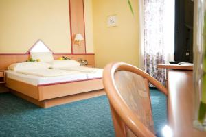 pokój hotelowy z łóżkiem i krzesłem w obiekcie Hotel Restaurant Osterbauer w mieście Neunkirchen