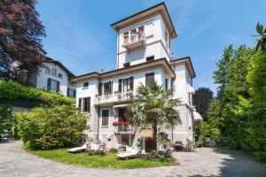 un gran edificio blanco con una palmera delante en BB Villa Adriana Varese, en Varese