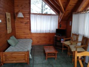 a bedroom in a log cabin with a bed and a desk at Calen-Hue in San Carlos de Bariloche