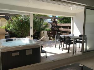 a patio with a tub and a table and chairs at Cap Locations Naturisme in Cap d'Agde