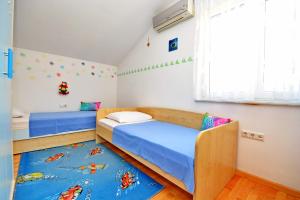 a bedroom with two beds and a blue rug at Apartments Andreja in Kožino